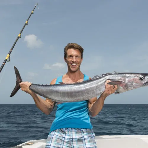 Happy client catch a fish and enjoy that moment on deep sea fishing tour Punta Cana